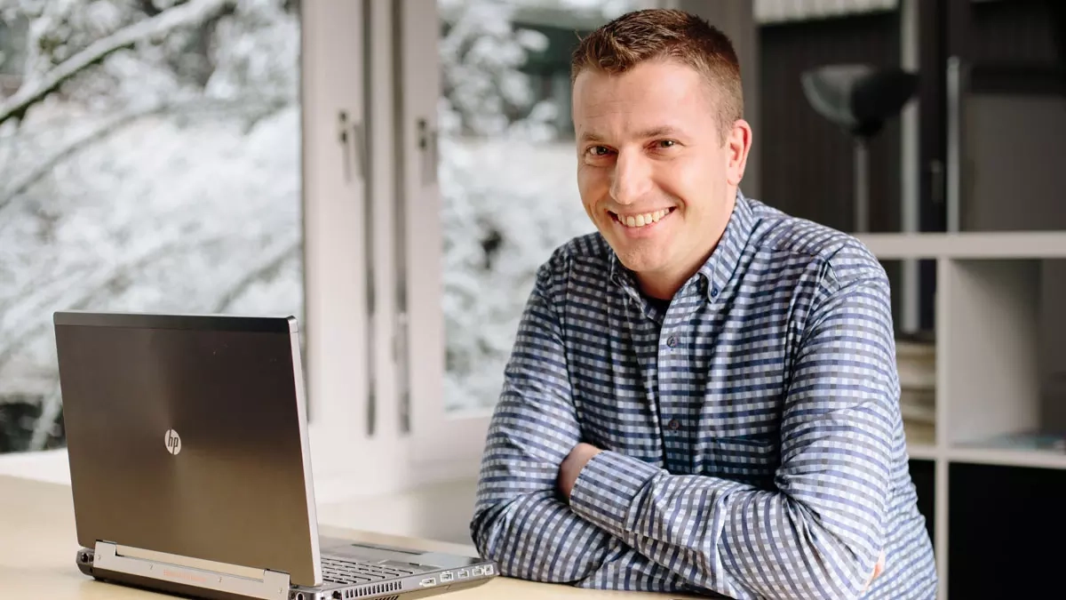 Moderne Büroatmosphäre mit lächelndem Mann am Laptop, ideal für Produktivität.