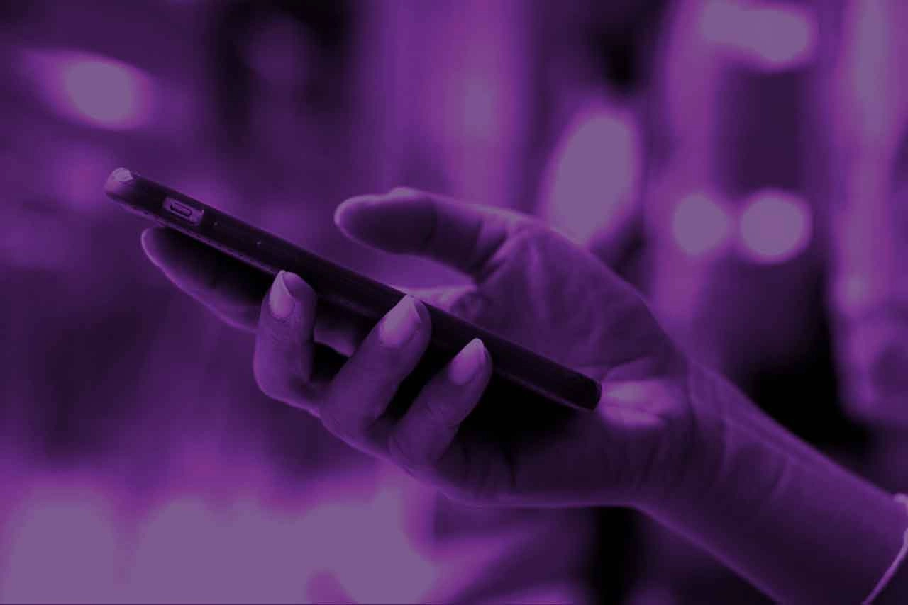 Smartphone in Hand, lila Hintergrund, moderne Kommunikation.