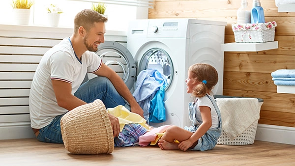 Vater und Tochter genießen Wäschezeit in moderner, gemütlicher Waschküche.