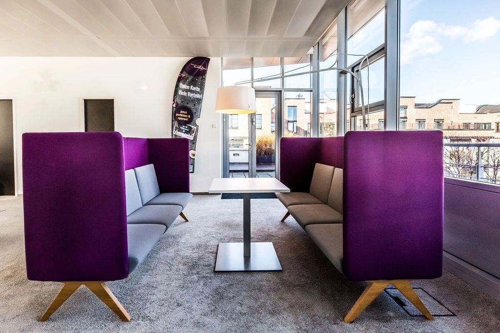 Moderne Lounge mit lila Sofas und Panoramafenster für inspirierende Meetings.
