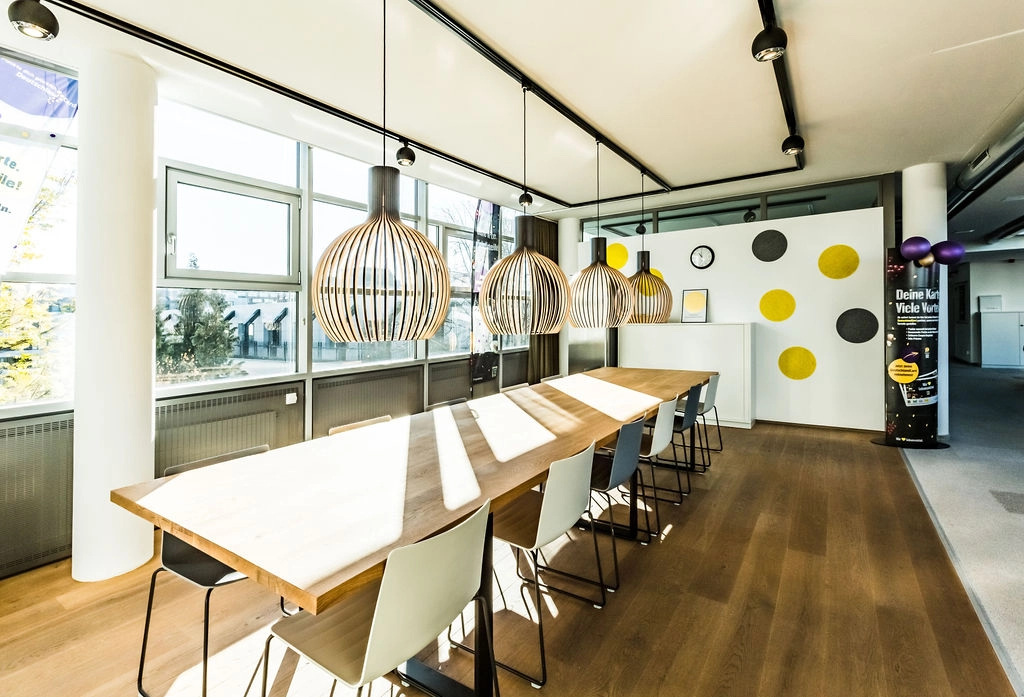 Moderner Konferenzraum mit stilvollen Lampen und hellem Holztisch.