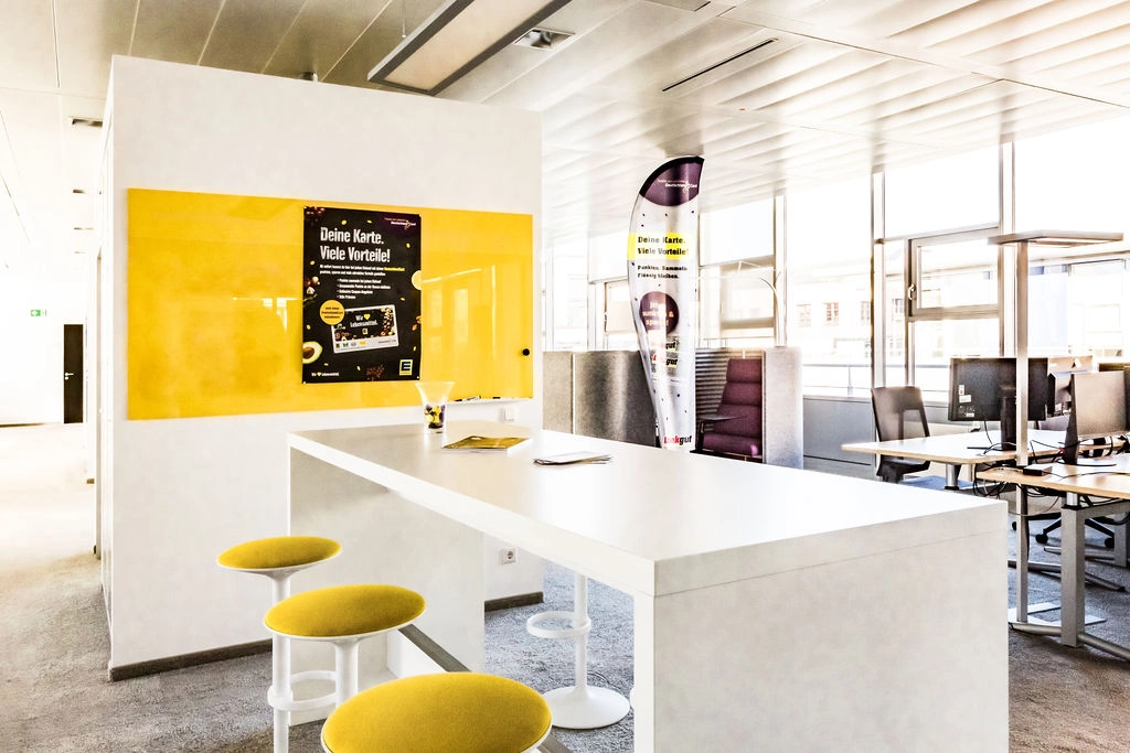 Modernes Büro mit gelben Akzenten und einladendem Besprechungsbereich.